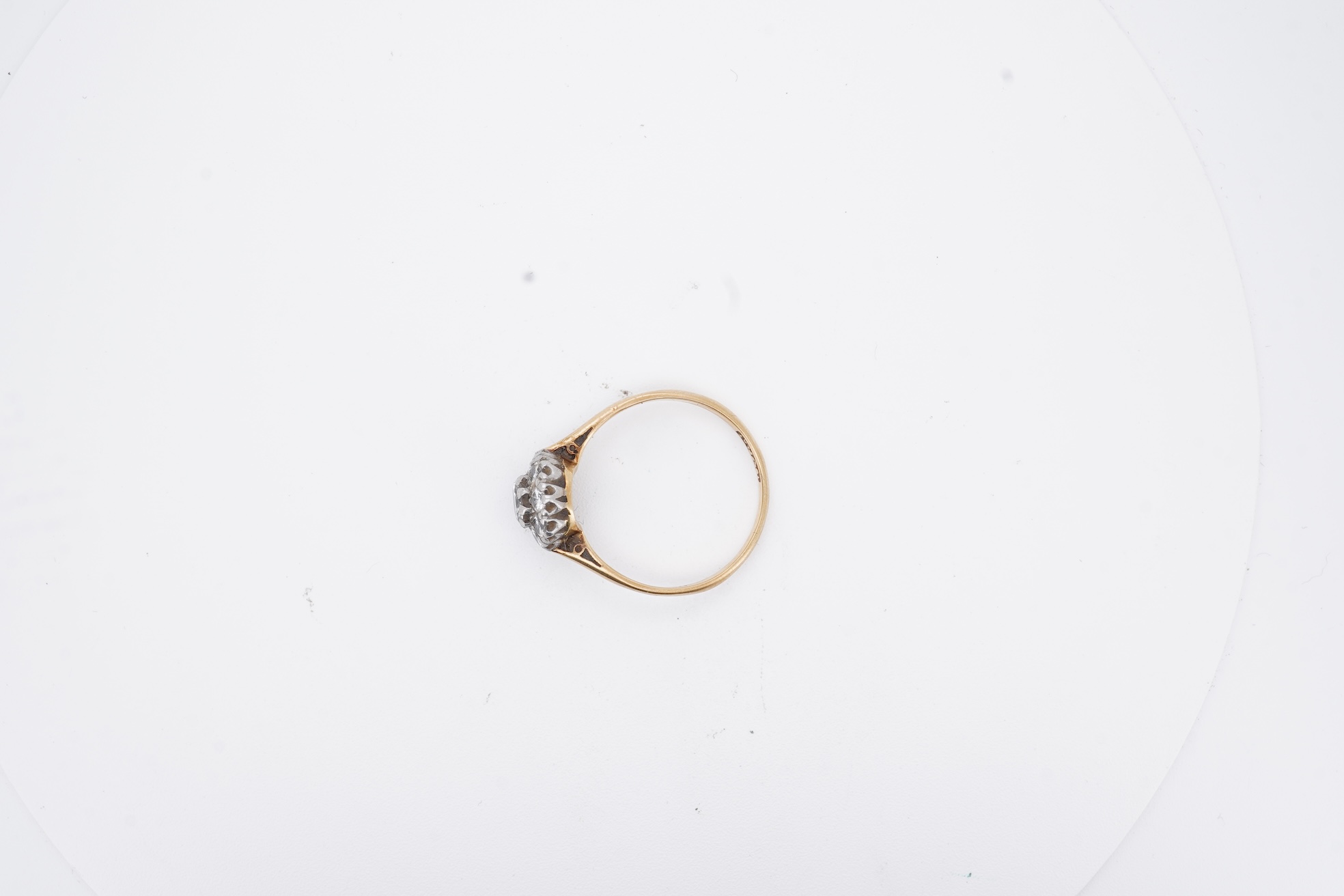 An early 20th century 18ct, plat. and nine stone diamond cluster ring, the central diamond weighing approximately 0.30ct, size Q, gross weight 3.1 grams.